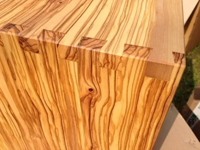 Ecke eines Holzquaders mit auffälliger Maserung und Zinkenverbindung