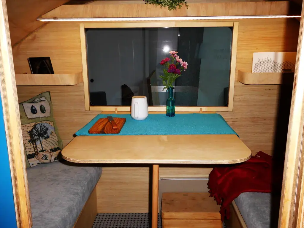 Kleine Sitzecke im Wohnwagen mit Tisch, Vase mit Blumen und Kissen